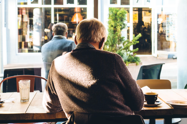 man in sweater sitting at a cafe facing away