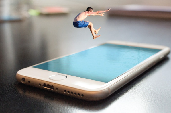 person in swim trunks leaping into blue iphone
