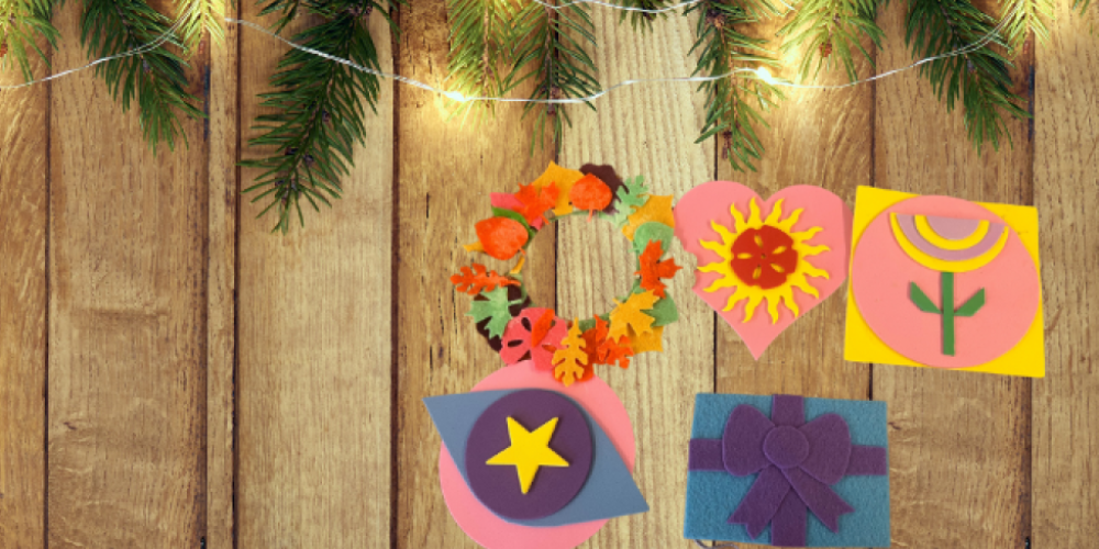 Various felt ornaments in front of a wood fence with pine draping and lights