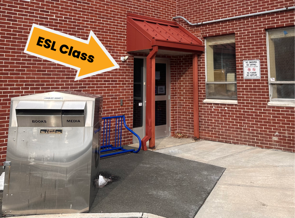 orange arrow pointing to entrance behind the outdoor book drop leading to ESL class location