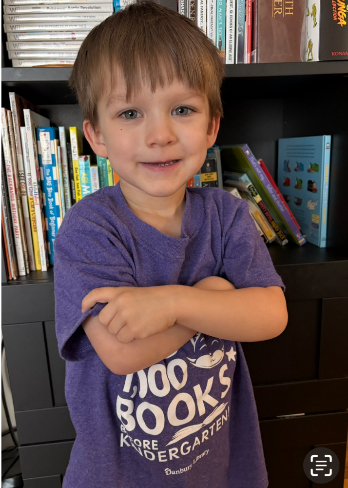 child crossing arms in front of bookcase