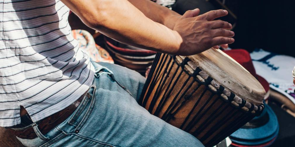 Person in white shirts and jeans playing drum