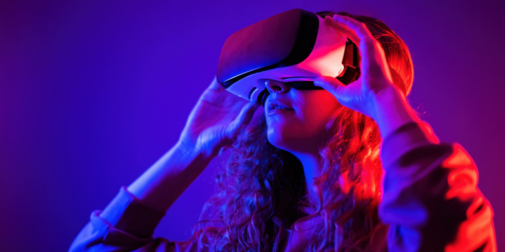 A girl looking through a VR headset with purple lighting behind her