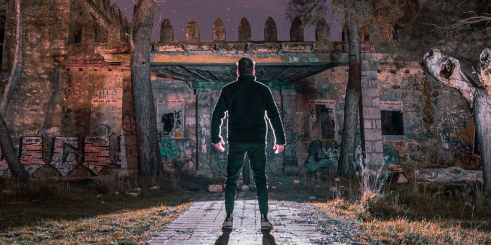 Man standing in front of an abandoned house.