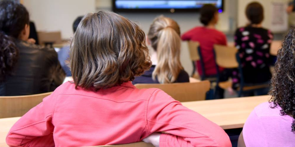A child in a class room facing the board